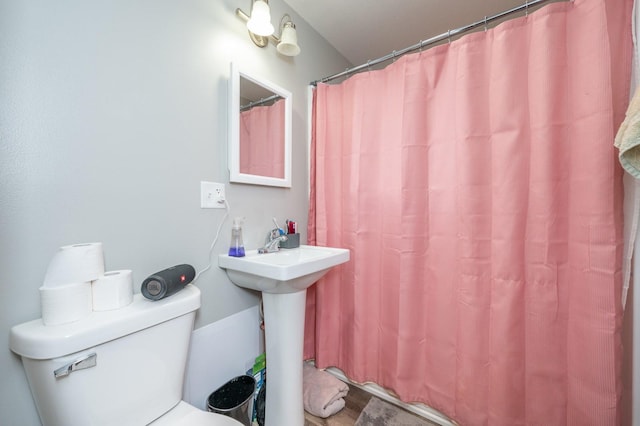 bathroom featuring a shower with curtain, toilet, and a sink