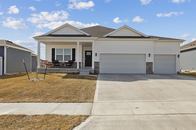 view of front of home with a porch, concrete driveway, a garage, and a front lawn