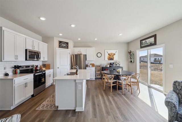 kitchen featuring decorative backsplash, appliances with stainless steel finishes, wood finished floors, and light countertops