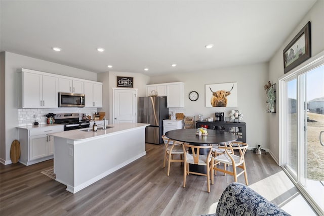 kitchen with decorative backsplash, appliances with stainless steel finishes, wood finished floors, and a sink