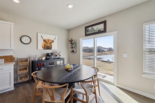 dining area with a healthy amount of sunlight, dark wood-style flooring, and baseboards