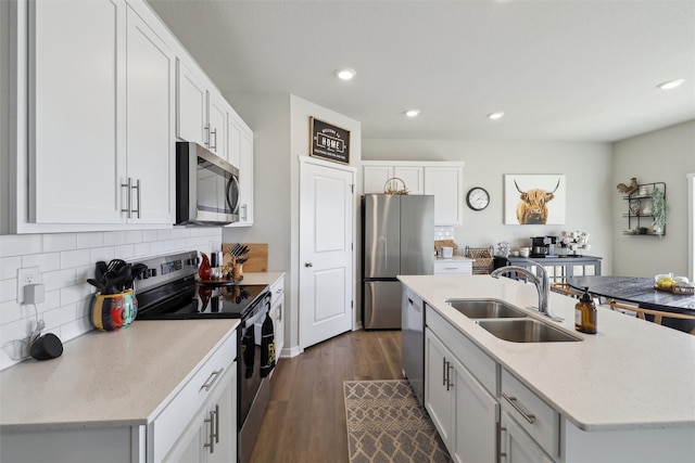 kitchen with backsplash, an island with sink, stainless steel appliances, white cabinetry, and a sink