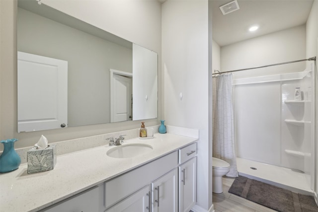 full bath with vanity, wood finished floors, visible vents, a shower stall, and toilet