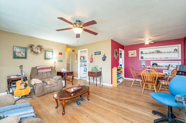 living room with a ceiling fan, baseboards, and wood finished floors