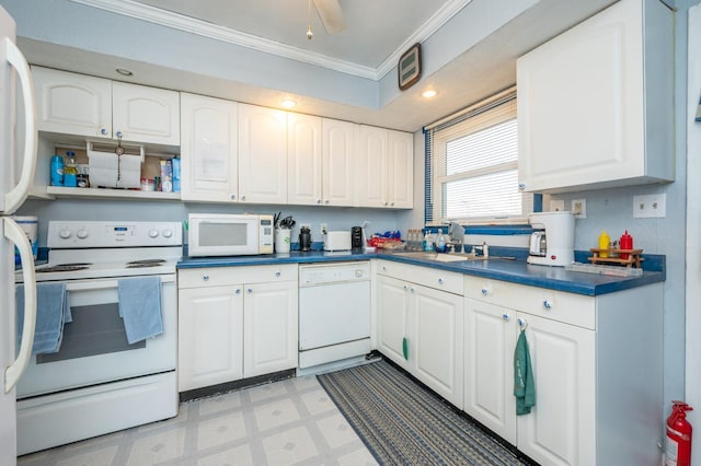 kitchen with dark countertops, light floors, ornamental molding, white appliances, and a sink