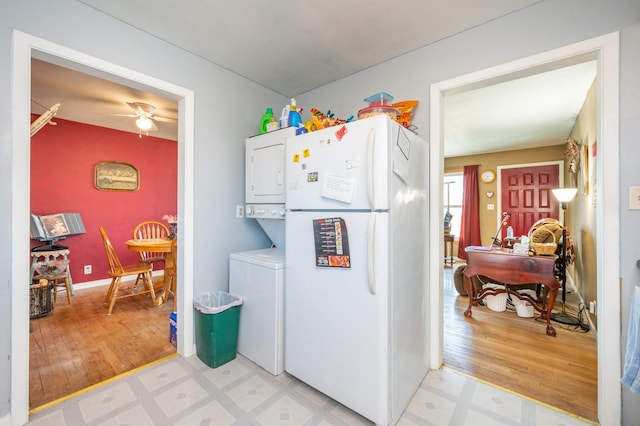 kitchen featuring stacked washer / drying machine, light wood-type flooring, freestanding refrigerator, and a ceiling fan