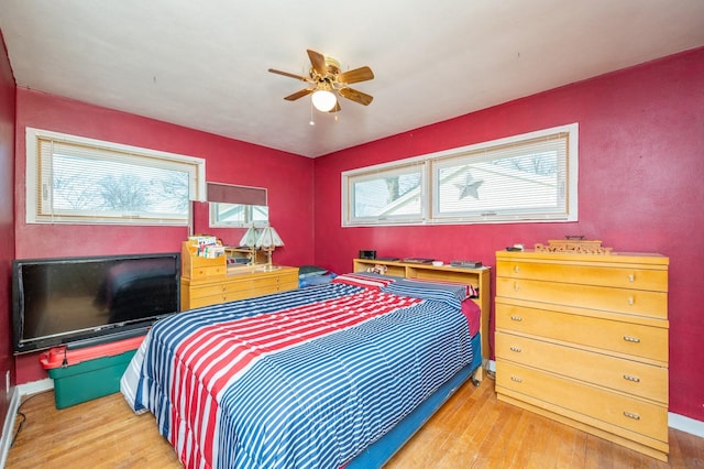 bedroom with multiple windows, wood finished floors, and a ceiling fan