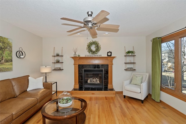 living area with visible vents, a textured ceiling, wood finished floors, ceiling fan, and a tile fireplace