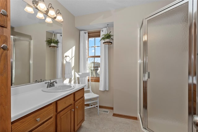 bathroom featuring vanity, a shower stall, and baseboards