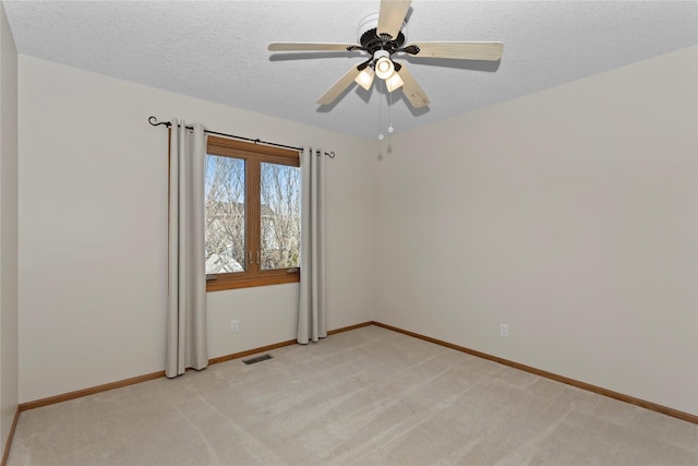 unfurnished room featuring baseboards, visible vents, ceiling fan, a textured ceiling, and light colored carpet