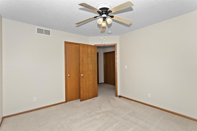 unfurnished bedroom with visible vents, light carpet, a textured ceiling, baseboards, and ceiling fan