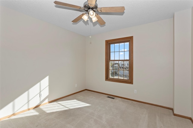 empty room featuring visible vents, light carpet, baseboards, and ceiling fan