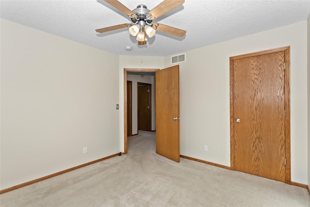 unfurnished bedroom featuring light colored carpet, baseboards, visible vents, and a textured ceiling