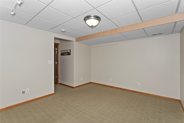 below grade area featuring a paneled ceiling, light colored carpet, visible vents, and baseboards