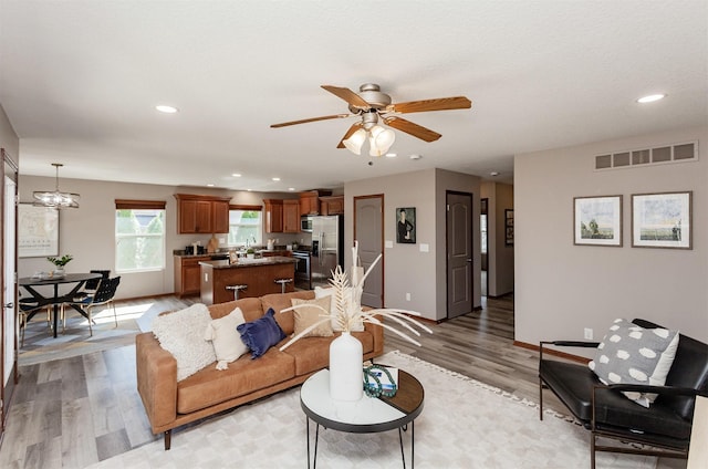 living area featuring light wood-style flooring, recessed lighting, and visible vents