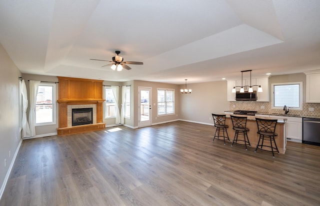 unfurnished living room featuring a wealth of natural light, a tray ceiling, dark wood finished floors, and a tiled fireplace