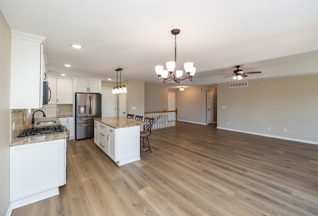 kitchen with visible vents, a sink, appliances with stainless steel finishes, a kitchen bar, and tasteful backsplash