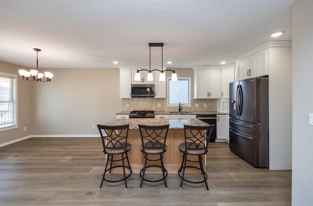 kitchen featuring tasteful backsplash, a kitchen island, stainless steel appliances, a breakfast bar area, and white cabinets