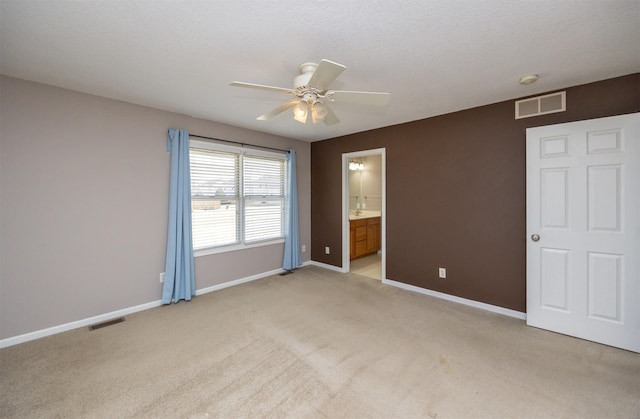 unfurnished bedroom with visible vents, light colored carpet, connected bathroom, and baseboards