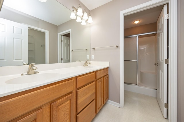 full bath featuring double vanity, a shower stall, baseboards, and a sink