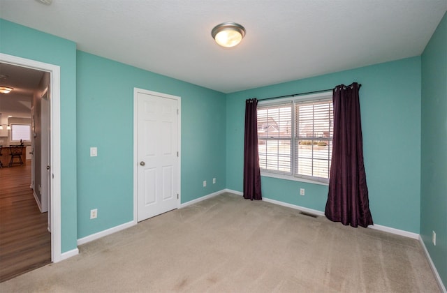 unfurnished bedroom featuring visible vents, carpet, and baseboards