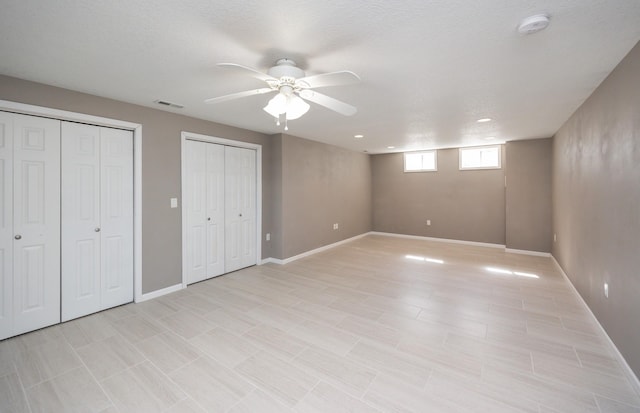 unfurnished bedroom with a ceiling fan, visible vents, multiple closets, and baseboards