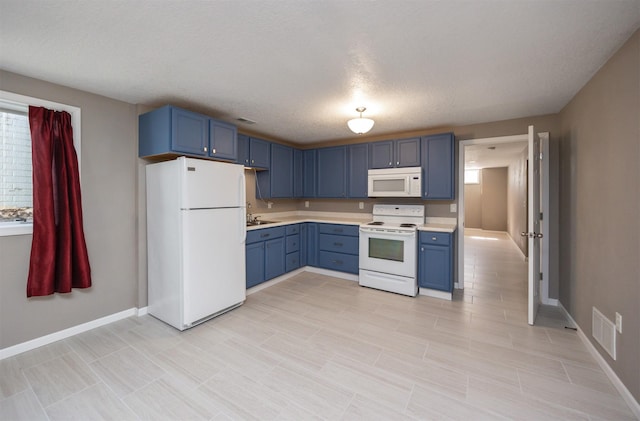 kitchen with white appliances, blue cabinetry, light countertops, and a sink