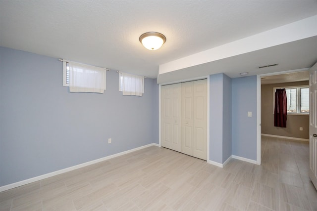 unfurnished bedroom with a closet, visible vents, a textured ceiling, and baseboards