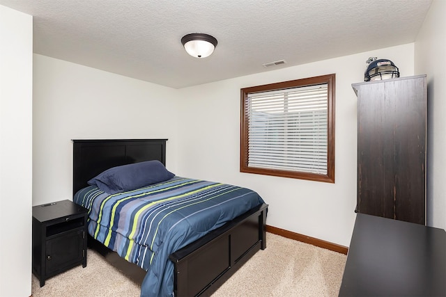 bedroom featuring visible vents, light colored carpet, and a textured ceiling