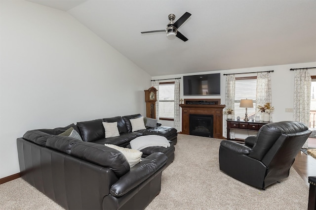 living area with a fireplace, baseboards, a ceiling fan, and vaulted ceiling