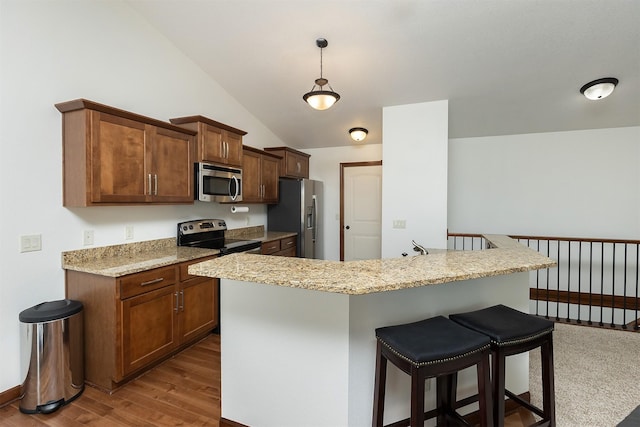 kitchen featuring dark wood-type flooring, pendant lighting, a breakfast bar, stainless steel appliances, and vaulted ceiling