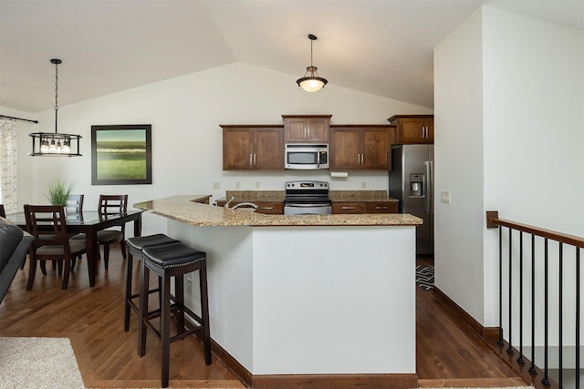 kitchen with appliances with stainless steel finishes, dark wood-style flooring, and hanging light fixtures