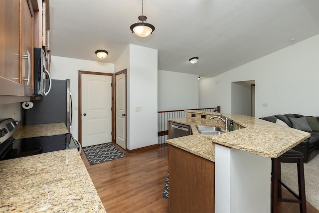 kitchen featuring dark wood-type flooring, a center island with sink, a breakfast bar area, stainless steel appliances, and a sink