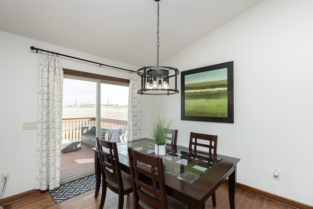 dining room featuring baseboards, lofted ceiling, an inviting chandelier, and wood finished floors