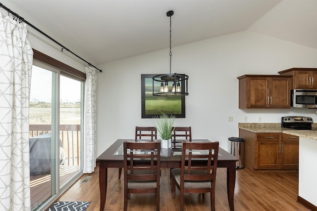 dining space with lofted ceiling, wood finished floors, and visible vents