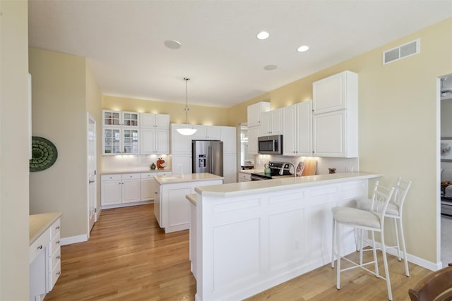 kitchen with visible vents, light wood-style flooring, an island with sink, stainless steel appliances, and tasteful backsplash