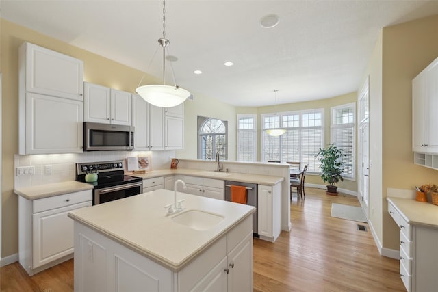 kitchen featuring a sink, appliances with stainless steel finishes, a peninsula, and white cabinetry