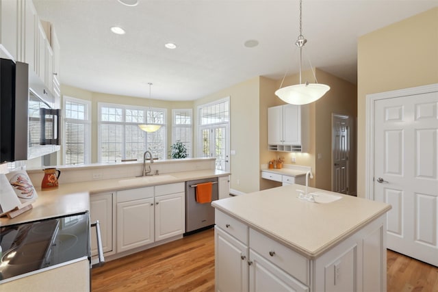 kitchen with light wood finished floors, white cabinets, appliances with stainless steel finishes, and a sink