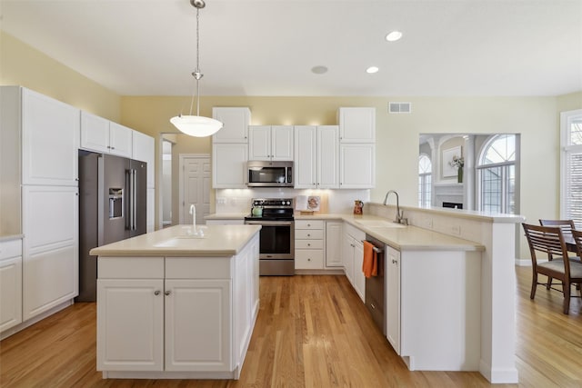 kitchen with visible vents, a sink, tasteful backsplash, appliances with stainless steel finishes, and a peninsula