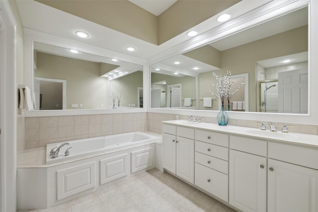 full bathroom featuring double vanity, a shower stall, a garden tub, and a sink