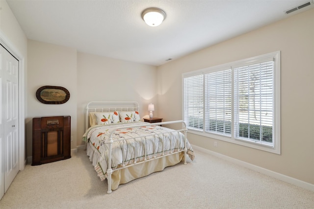 bedroom with a closet, visible vents, carpet, and baseboards