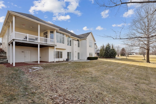 back of property with a balcony, a patio area, and a lawn