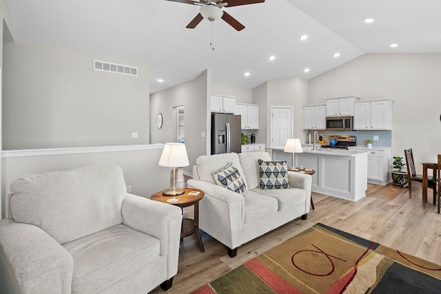 living room featuring a ceiling fan, visible vents, recessed lighting, vaulted ceiling, and light wood-style floors