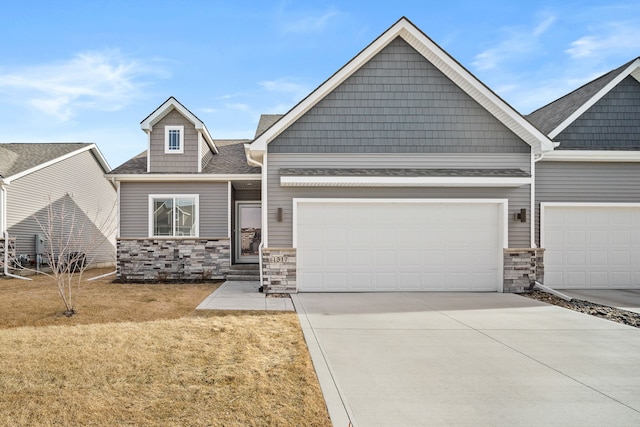 view of front of property with stone siding, a front yard, an attached garage, and driveway