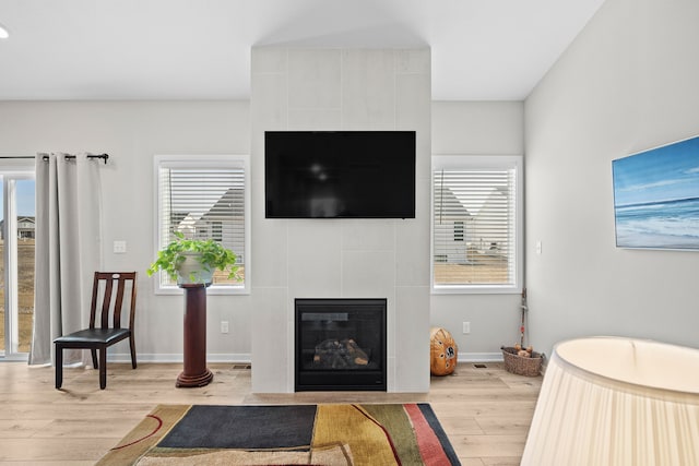 living area with baseboards, a healthy amount of sunlight, light wood-style flooring, and a fireplace