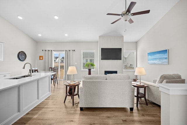 living room featuring recessed lighting, light wood-style flooring, a tile fireplace, and ceiling fan