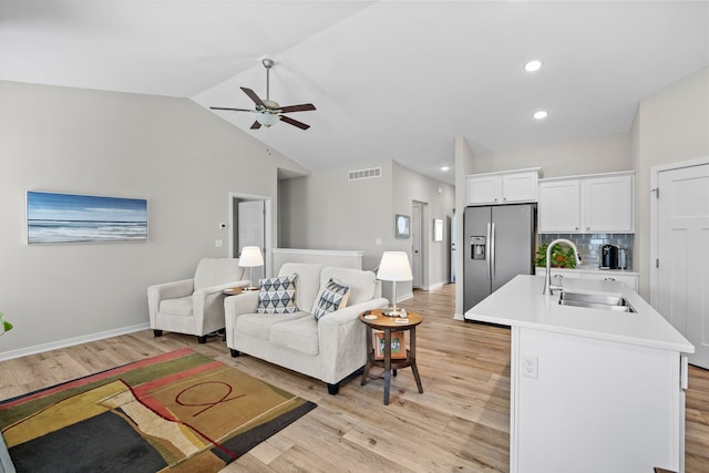 living room with visible vents, baseboards, light wood finished floors, lofted ceiling, and ceiling fan