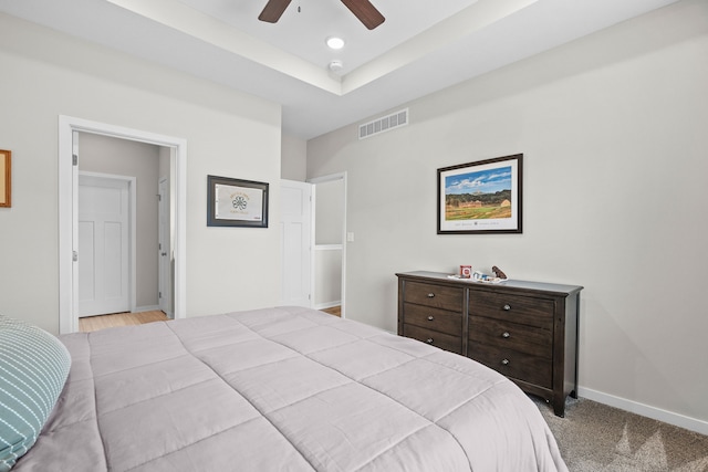 carpeted bedroom featuring visible vents, a tray ceiling, recessed lighting, baseboards, and ceiling fan