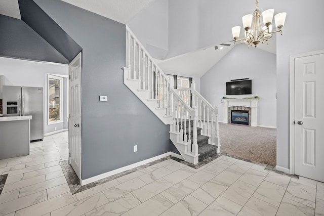 staircase with baseboards, a fireplace, marble finish floor, and high vaulted ceiling