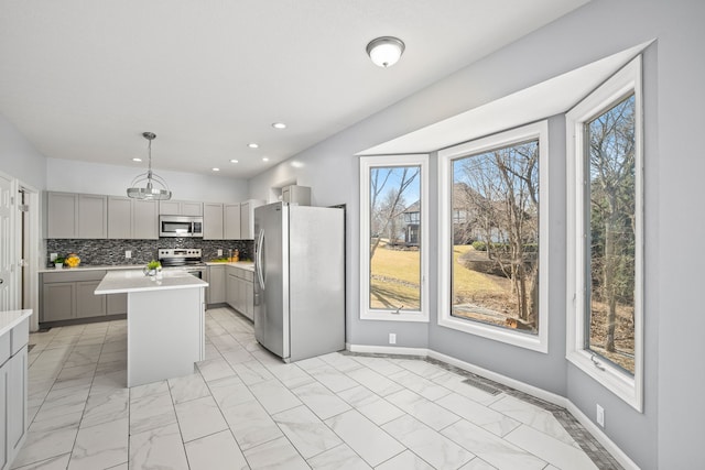 kitchen with tasteful backsplash, light countertops, gray cabinets, appliances with stainless steel finishes, and marble finish floor